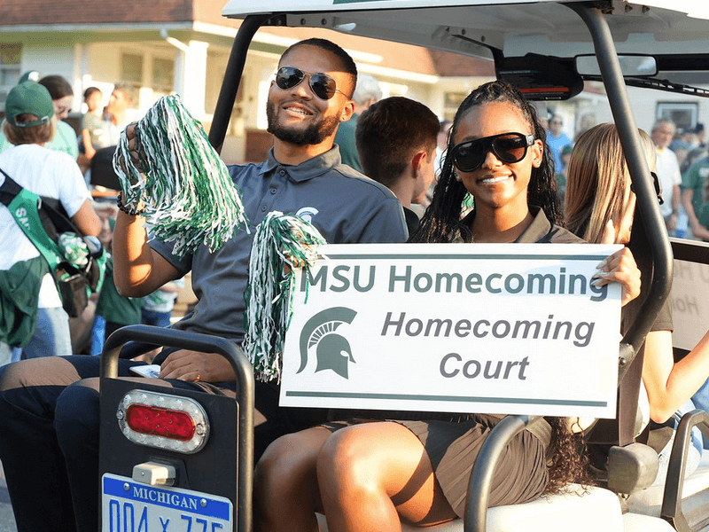 Student in a gold cart at a parade